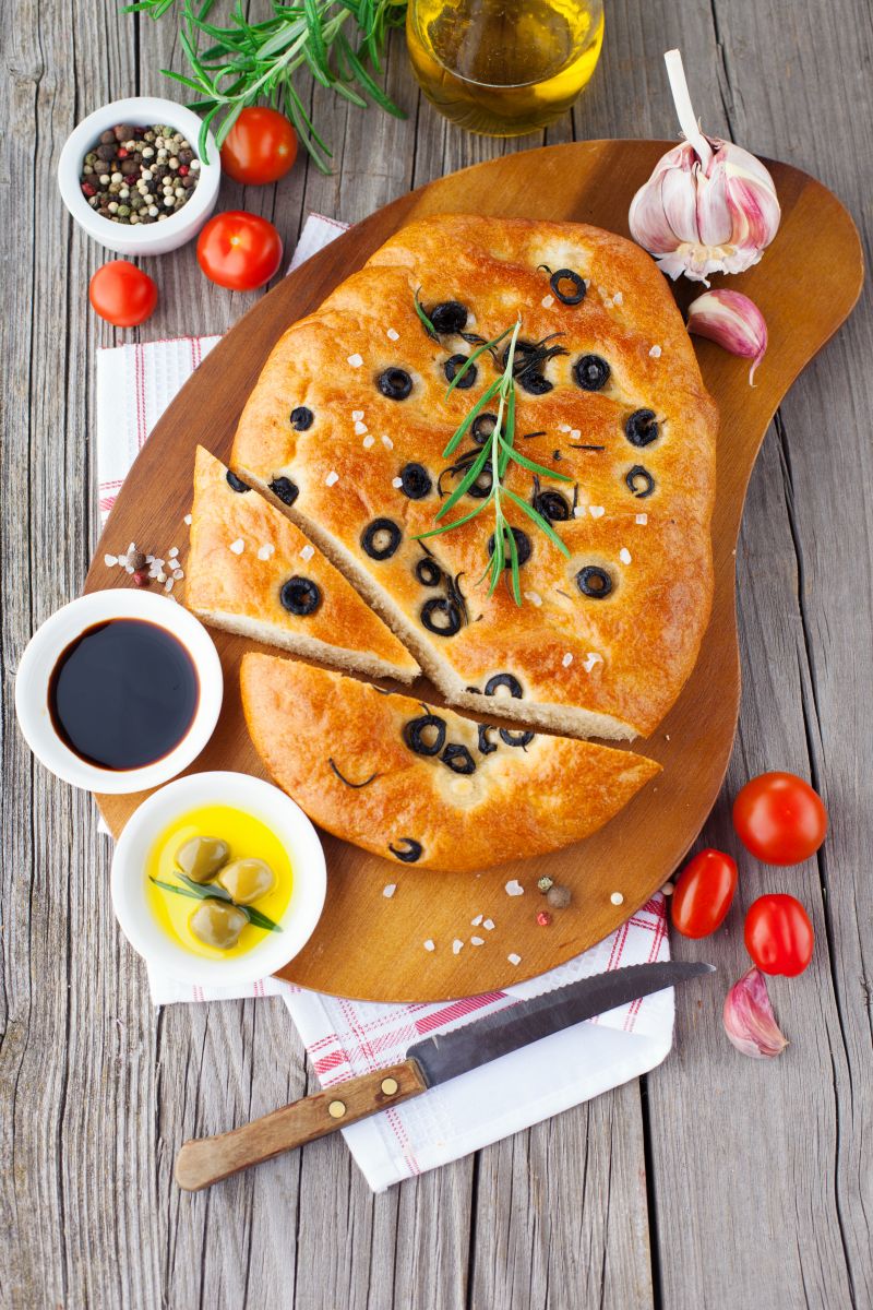 Freshly baked traditional Italian focaccia bread with rosemary and black olives