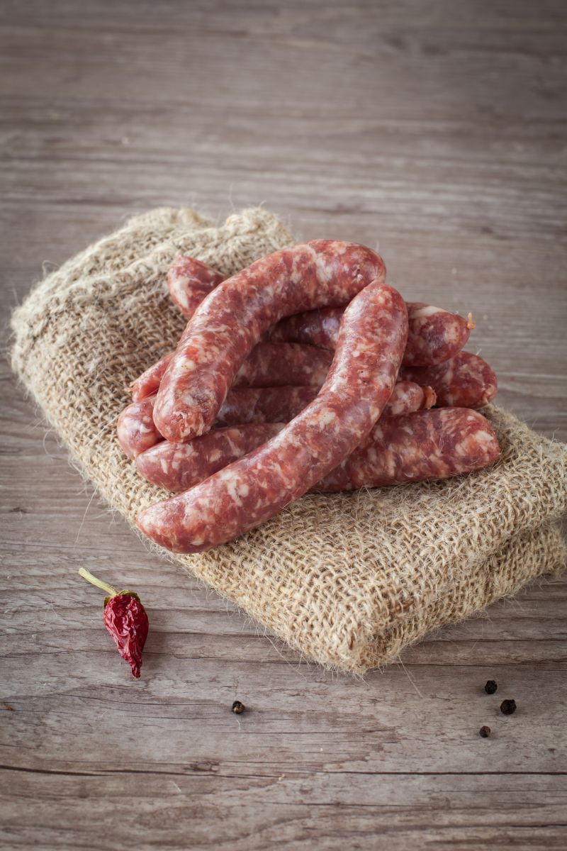 Fresh and tasty italian sausage on wooden background